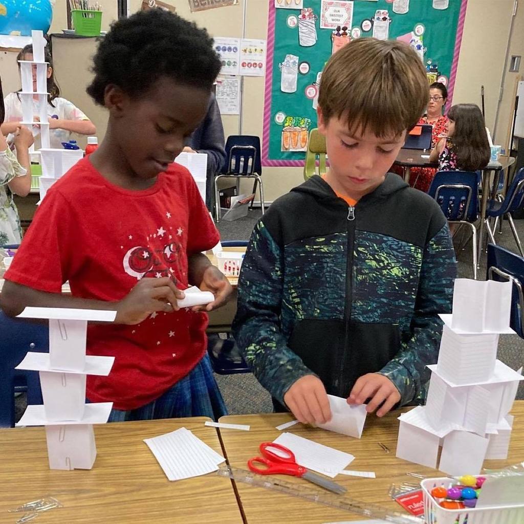 two boys create paper towers in class