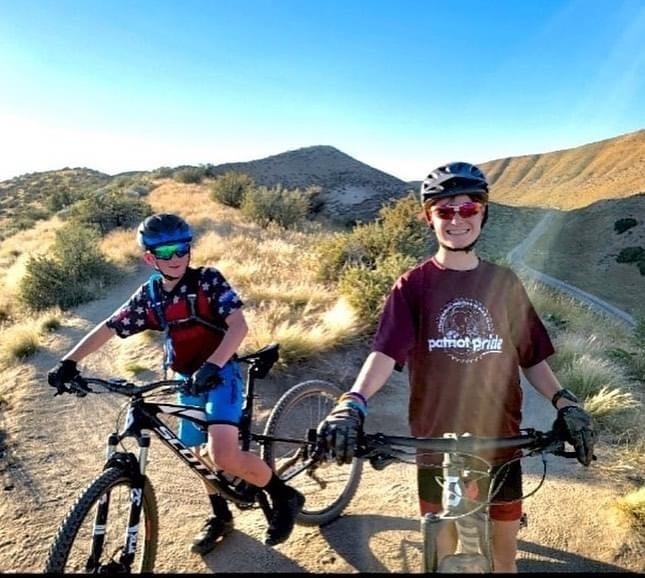 two mountain bikers pose on hill
