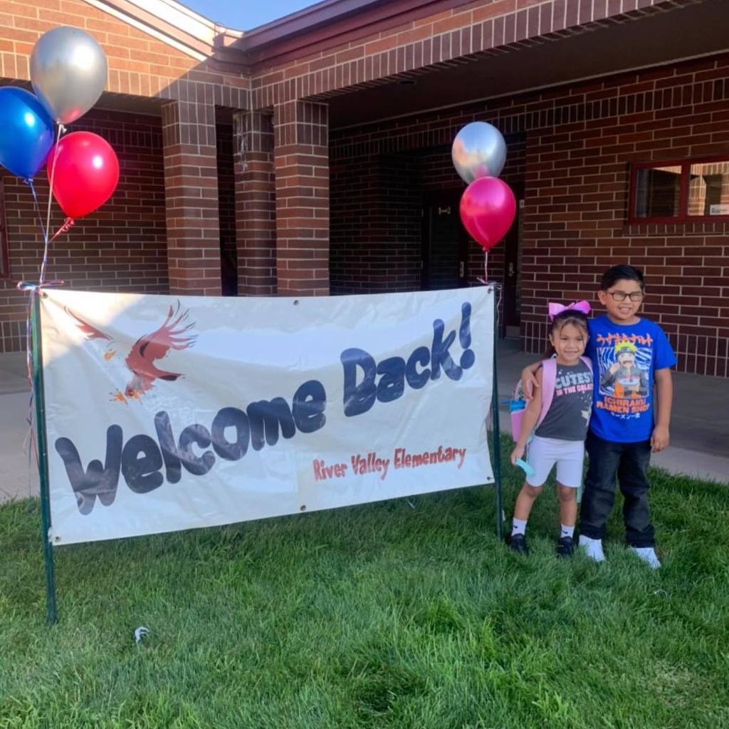 welcome back andrus - two students standing in front of sign